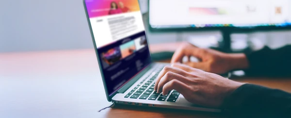 Hands typing on a laptop showing a web page